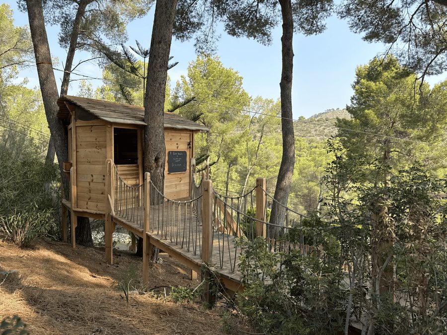 Cabaña con puente entre árboles en bosque mediterráneo